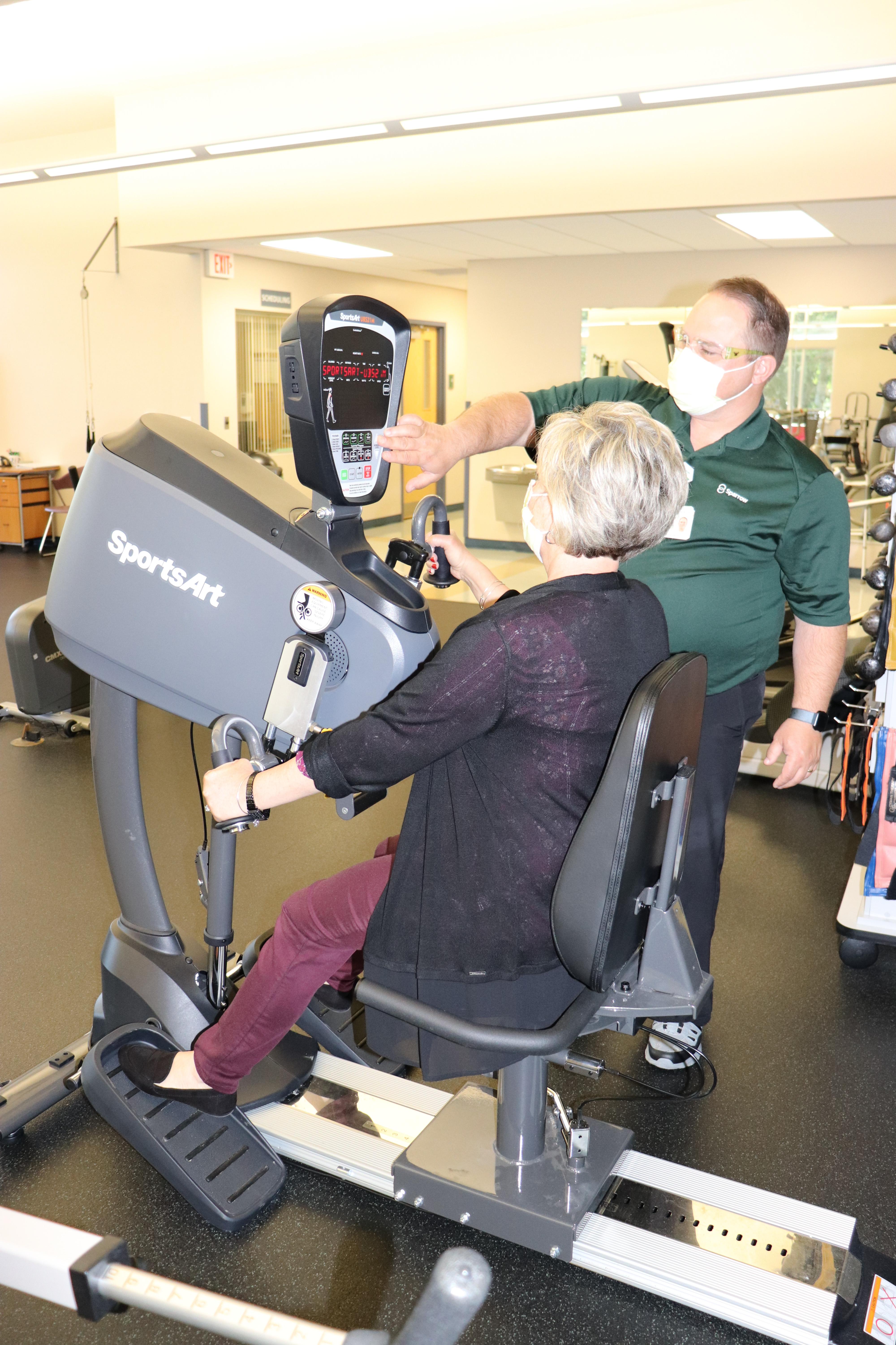 : Monte Shearer, Sparrow Carson Physical Rehabilitation Clinic Manager, sets the new Upper Body Cycle for a patient as she begins therapy.